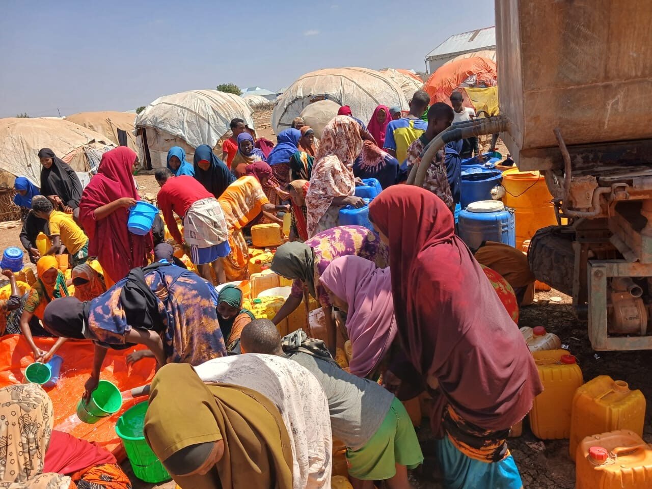 Families collecting water from a distribution point at a displacement site